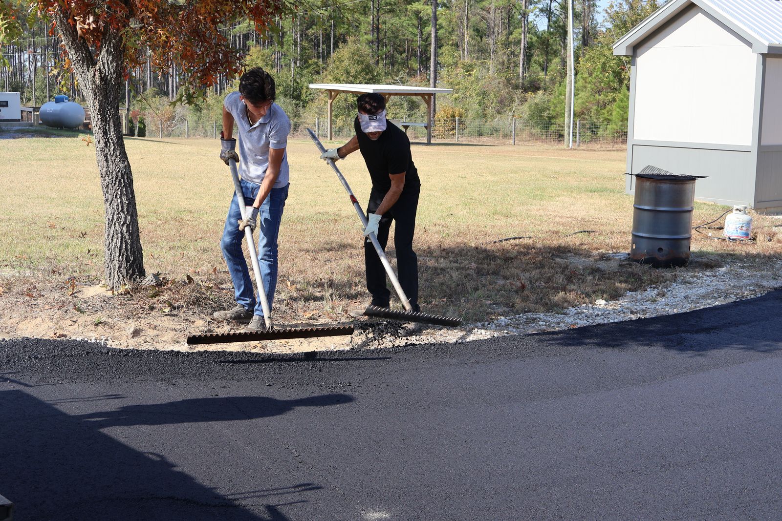 Bryerboyz crew hand-raking the edge of a freshly laid asphalt mat