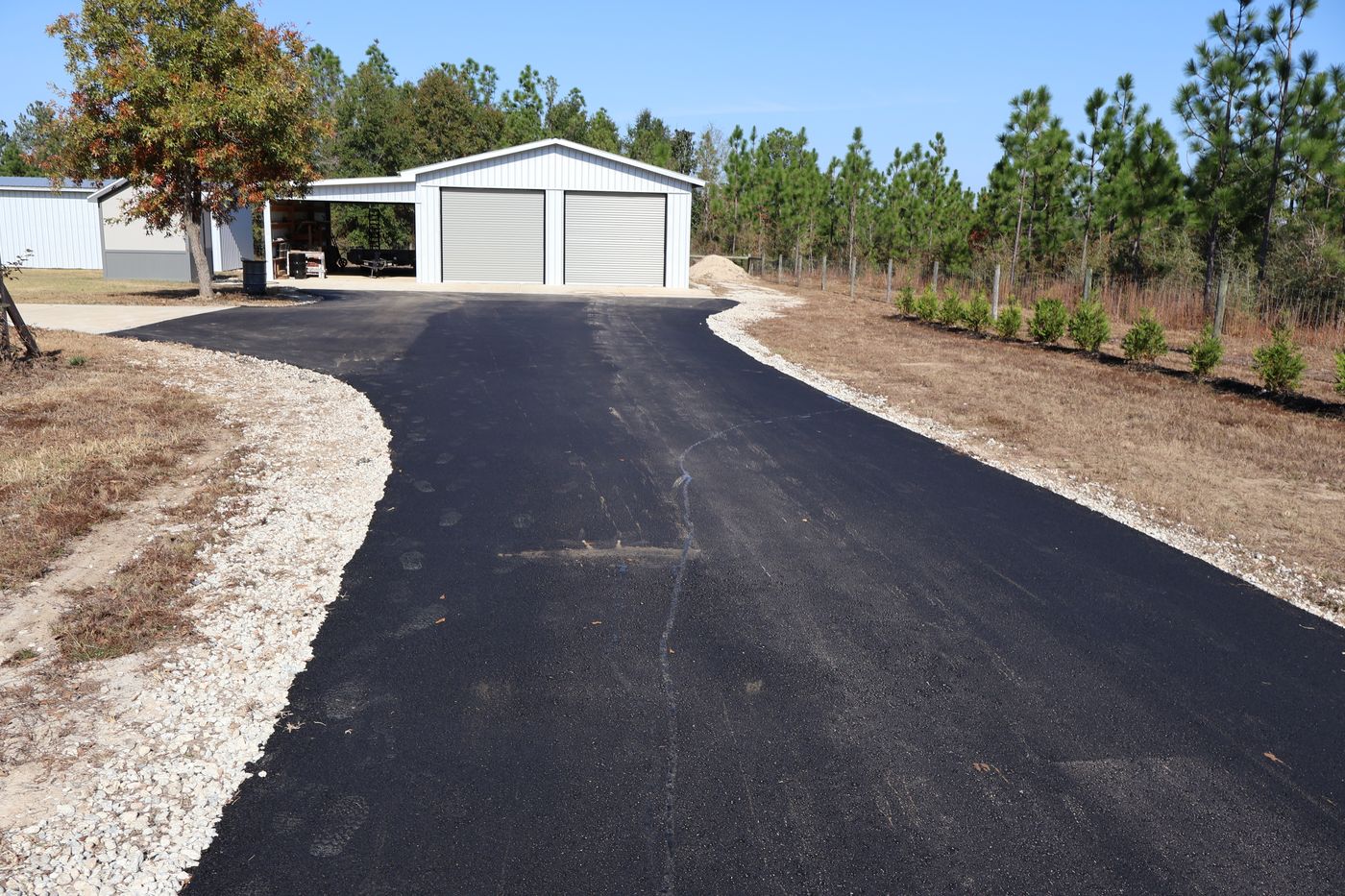 Freshly paved asphalt driveway leading to a white garage