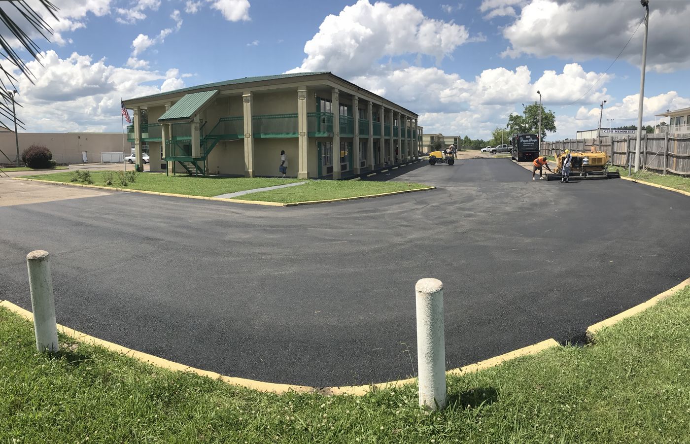 Crew repaving a commercial parking lot with paver, roller and dump truck