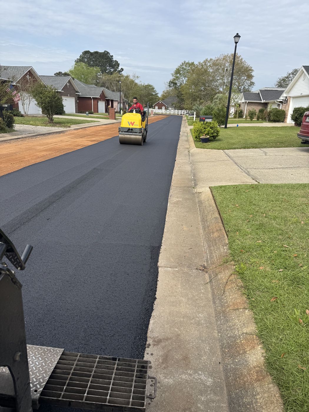 Fresh asphalt street with roller and crew at work