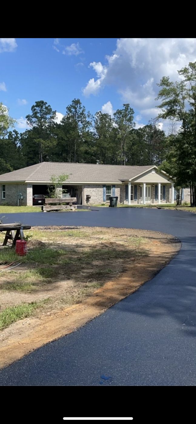Fresh asphalt circular driveway in front of a brick home